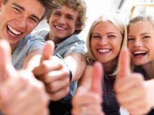 Happy guys and girls expressing happiness by showing thumbs while smiling