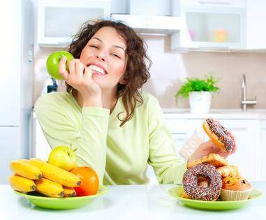 Diet. Beautiful Young Woman choosing between Fruits and Sweets